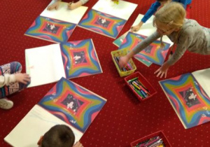 Dzieci leżąc na dywanie rysują swoje wizualizacje świata wokół głoski y